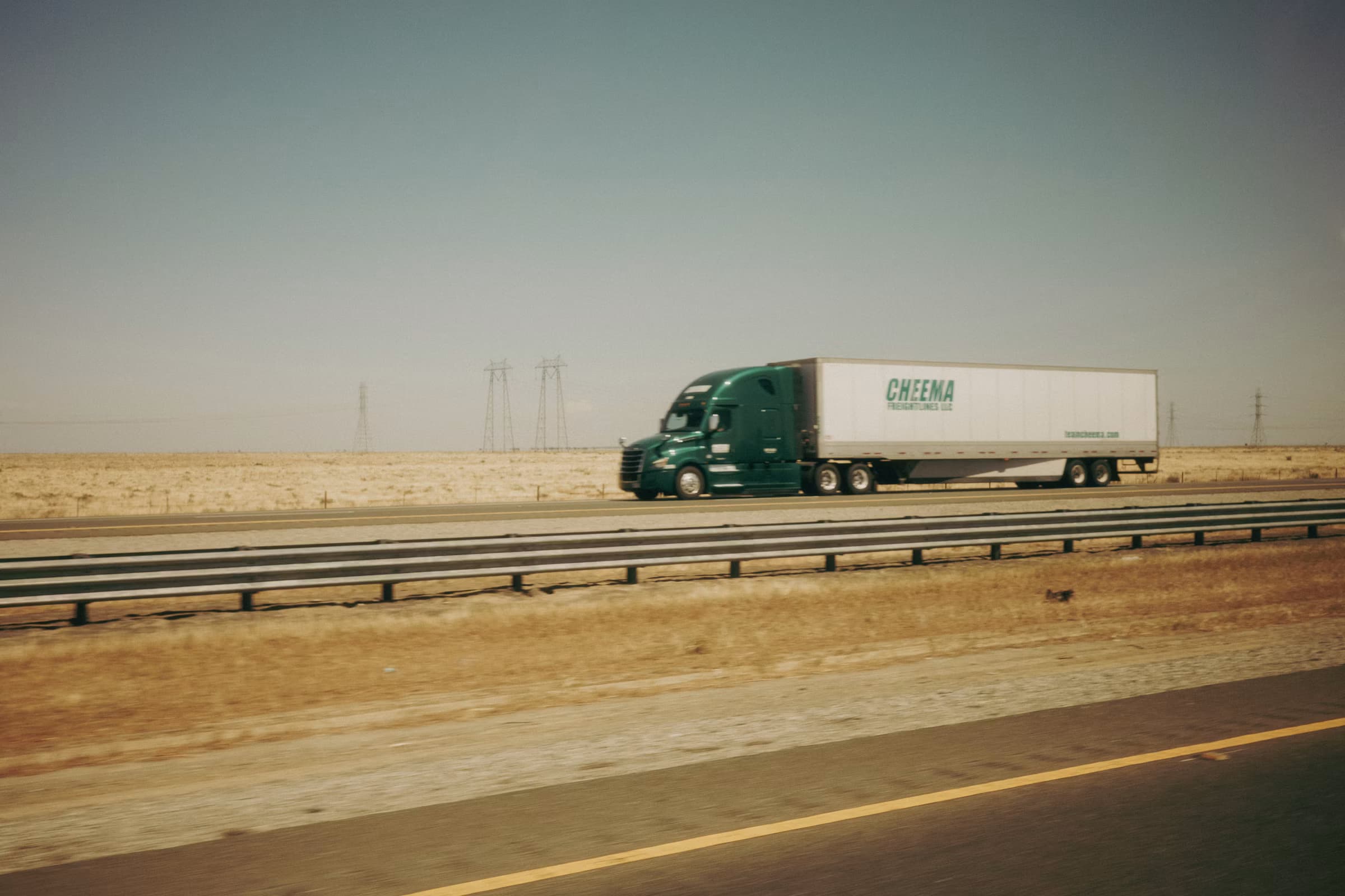 Heavy truck moving across an open highway at golden hour